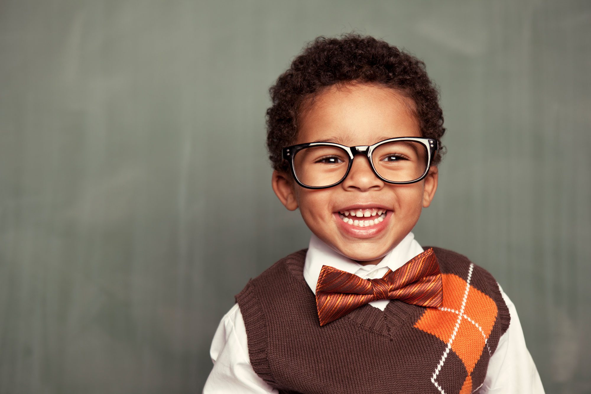Happy toddler smiling wearing glasses and a bow tie.