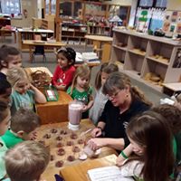 Group of children with teacher in a classroom working on a project together.
